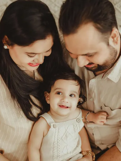 A happy and relaxed family photo, capturing a candid moment of smiles and connection between the parents and their adorable baby.