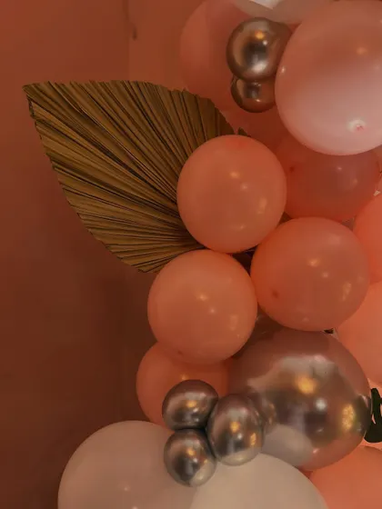 A detail shot of the balloon garland, showing the mix of pink, white, and chrome balloons with a touch of greenery. We focus on the small details to create a cohesive look.