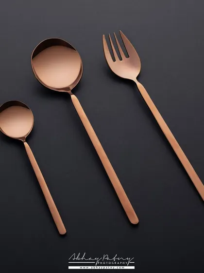 The same modern cutlery set, but this time photographed on a stark black background. This creates a dramatic, high-contrast image that emphasizes the product's metallic sheen and luxurious feel.