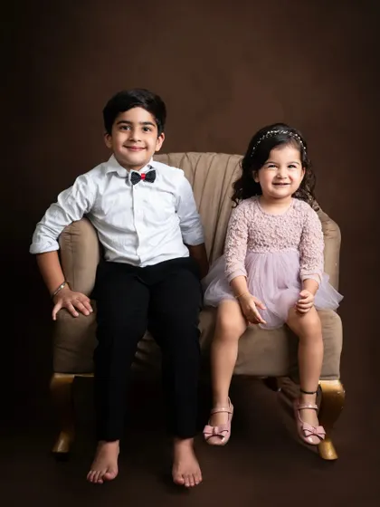 A classic portrait of a brother and sister, sitting together and sharing a smile.