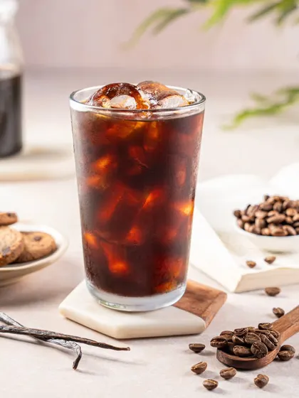 A refreshing glass of iced Americano for Zepto Cafe's beverage menu. The image is bright and clean, highlighting the condensation on the glass to convey a cool, refreshing feeling.