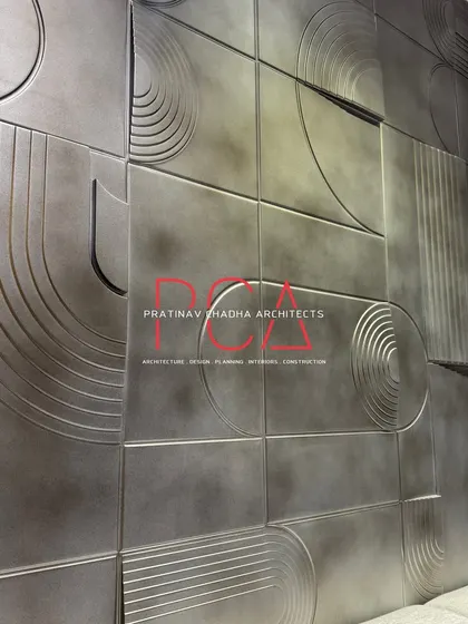 An angled close-up of the geometric accent wall, showing how light plays across its textured, metallic surface.