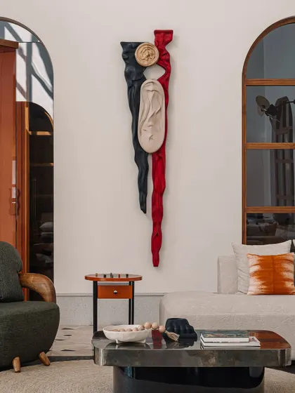 The 'Squal Man' sculpture, carved in ashwood with red and black stains, serves as a powerful focal point in the informal living room. It's a testament to our belief in integrating meaningful art into our architectural spaces.