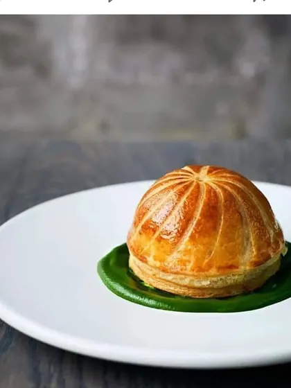 A classic chicken or mushroom vol-au-vent. This puff pastry dish is served on a bed of green sauce, a timeless and elegant appetizer.