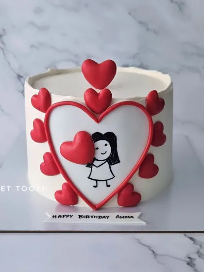 A doodle cake for Amma's birthday. This simple yet heartfelt design features a hand-drawn girl holding a big heart, surrounded by smaller fondant hearts.