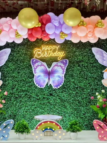 A close-up of the backdrop with a neon 'Happy Birthday' sign and fairy cutouts.