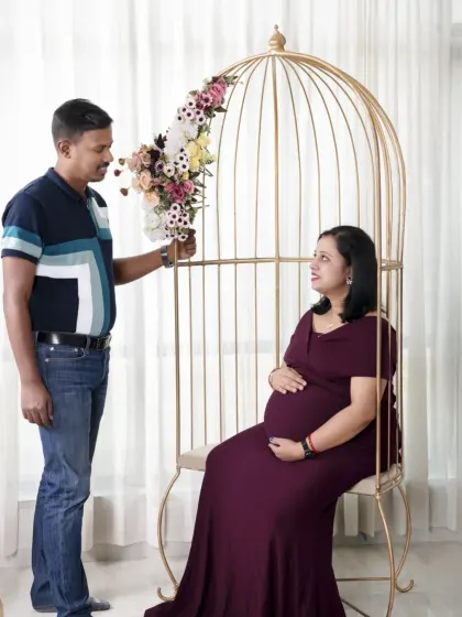 A romantic scene using our golden birdcage prop. The father-to-be presents flowers to his partner, creating a fairytale-like moment.