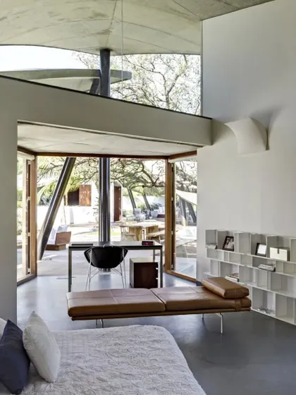 The bedroom in 'The Leaf House' is a serene space where the interior flows into the exterior. The unique form of the roof and the large glass openings make you feel completely immersed in nature.