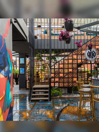 The completed bar area, where industrial metalwork, earthy terracotta, and colorful art come together. The gold bar stools add a touch of glamour to the eclectic and textured space.