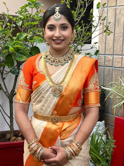 This bride's joyful expression is the perfect result. The makeup, with its soft smokey eye and bold lip, is designed to match her vibrant personality and the bright colors of her saree.