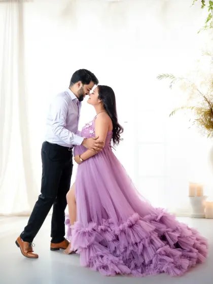 A romantic and light-filled couple's portrait. The flowing lavender gown and the soft, airy studio create a dreamy and ethereal atmosphere.