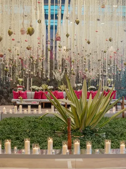 A daytime event in Udaipur featuring thousands of suspended floral strings, creating a magical, swaying canopy over the guest seating and bar areas.