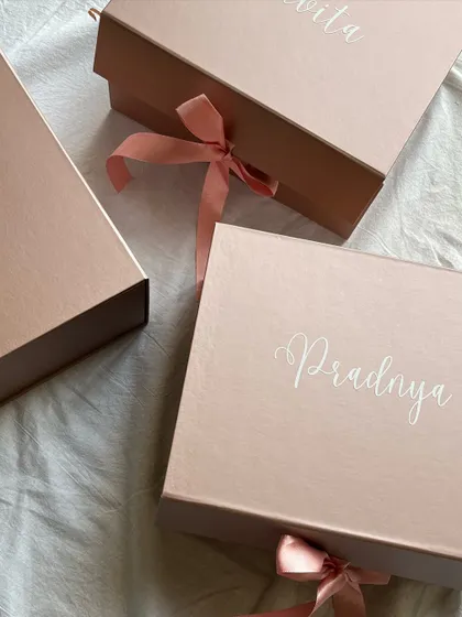 The beauty is in the details. These elegant rose gold boxes are personalized with each bridesmaid's name in a beautiful script, creating a sophisticated and personal first impression before they even see the gifts inside.