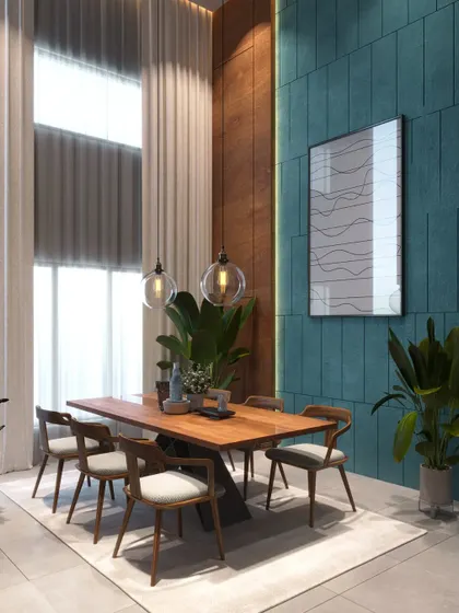 A dining area in a double-height room with floor-to-ceiling curtains. The design uses a simple wooden table and a textured teal accent wall to add color and depth.