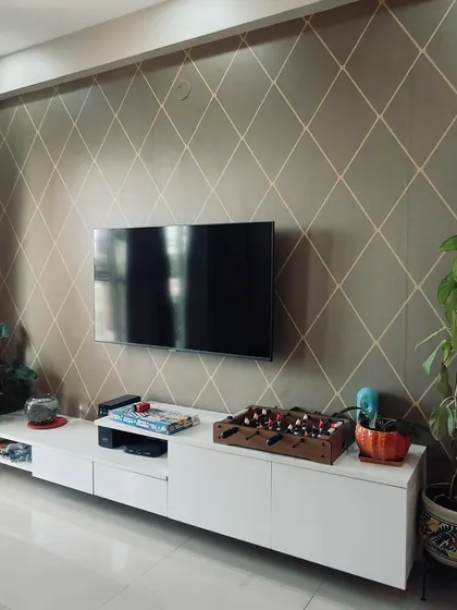 A minimalist white TV console set against a wall with a subtle geometric pattern, complemented by lush indoor plants for a fresh and modern look.
