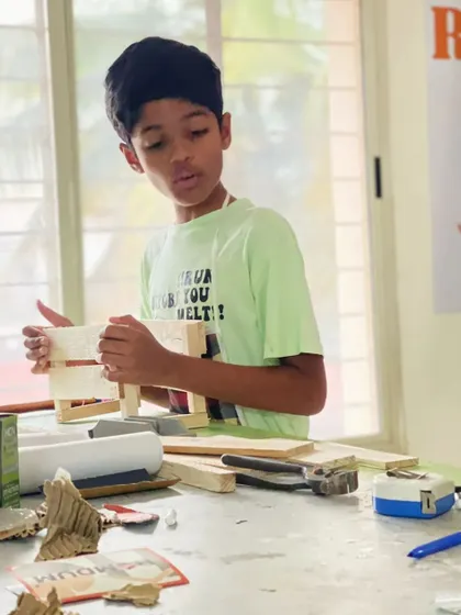 A young builder inspects his work on a wooden crate. This project is a fantastic introduction to the world of carpentry and structural design for children.