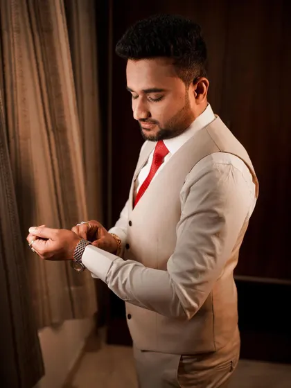 A groom adjusts his cufflink, a classic getting-ready shot that captures the final touches before the reception.