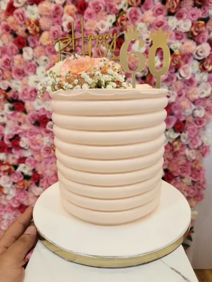 Another angle of the tall, ridged 60th birthday cake, held to show its impressive height and elegant design.
