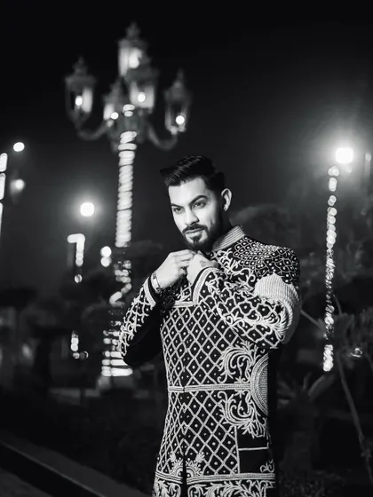 A dramatic black and white photo that highlights the silhouette of the Indo-Western jacket against the night lights. It's a modern take on royal attire.