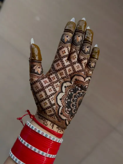 A stunning back-of-hand design with a full 'jaal' or net pattern and a bold mandala at the wrist. The bride's red 'chooda' bangles add to the festive look.