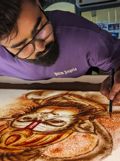 Adding color and detail to my Hanuman ji sand art with a fine brush.