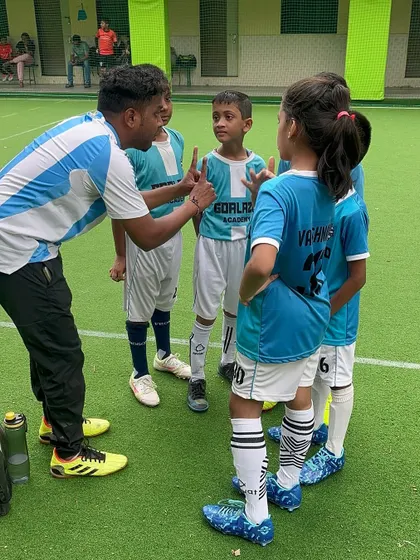 A coach giving tactical instructions to the Under-9 team during a break in play. Clear communication is vital.