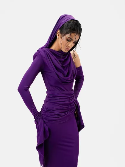 A creative pose with the gown's hood. The wet-look tendrils of the hair are still visible, adding a layer of texture to this high-fashion shot.
