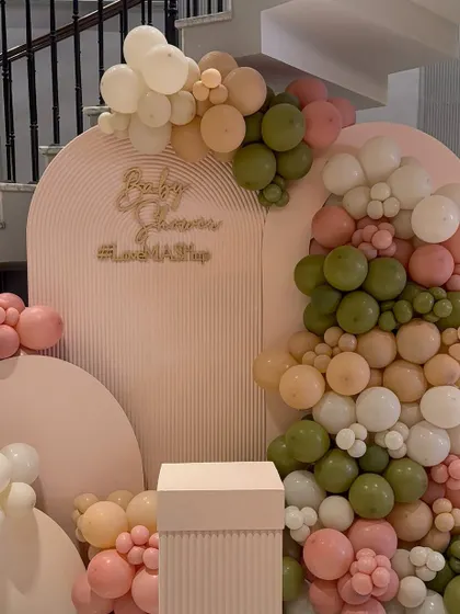 Another beautiful backdrop for a baby shower, this one featuring a ribbed texture, gold lettering, and an organic balloon garland in muted tones of olive green, peach, and pink.