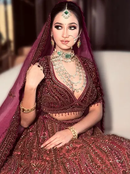 A full length view of this royal bridal look. The makeup is designed to complement the heavily embellished lehenga, creating a cohesive and breathtaking final image.