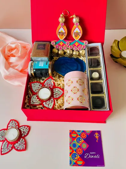 Our classic red square box with a magnetic closure, curated with a mix of traditional and modern items like chocolates, a tin jar, and festive hangings.