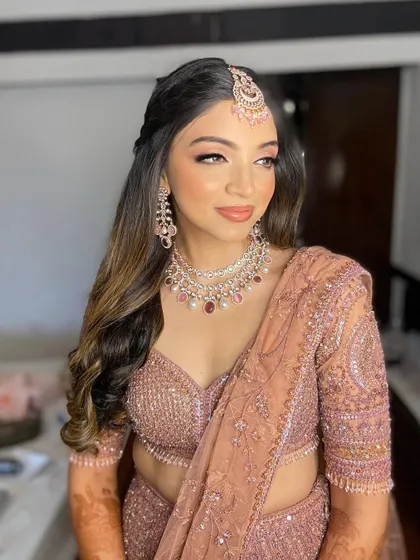 This side view shows how the makeup complements her soft curls and the intricate details of her lehenga.
