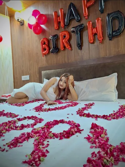 A birthday surprise setup with the bed covered in rose petals spelling out 'I LOVE YOU'.