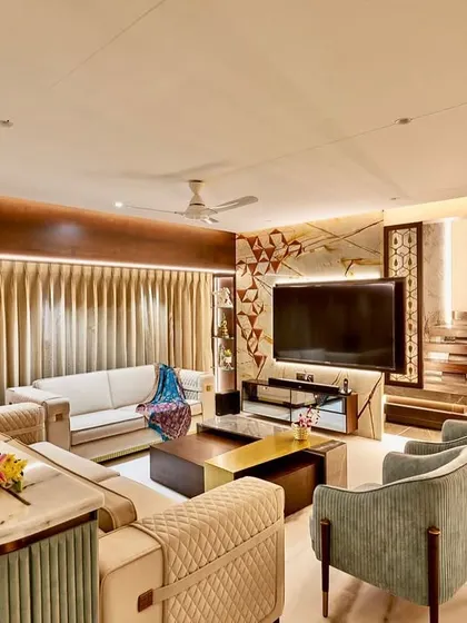 This living room combines traditional warmth with modern luxury. The design features a custom media wall, a staircase with integrated lighting, and a mix of quilted and smooth upholstery for textural variety.