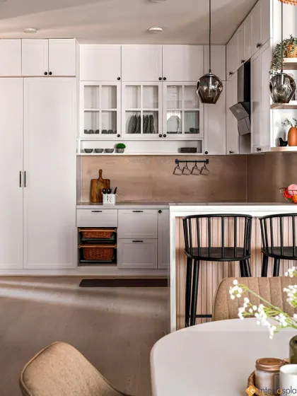 An overview of the open-plan kitchen and dining area. The white cabinets and light wood floors create a seamless flow between the two spaces, perfect for entertaining.