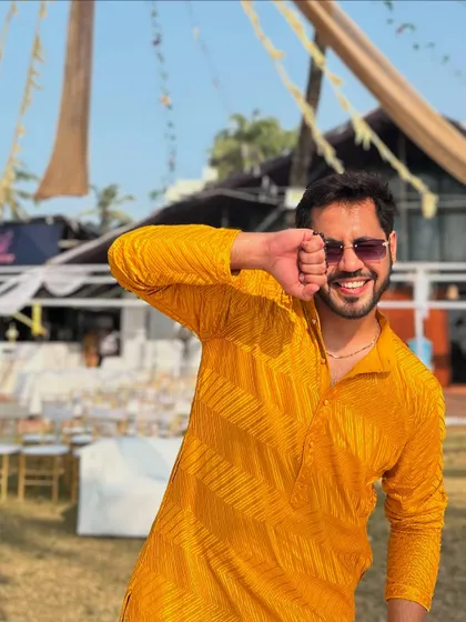 A fun, candid pose at a beachside Haldi event. The yellow kurta perfectly matches the sunny, happy vibe.