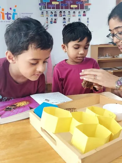 A teacher shows two boys a piece of real honeycomb. Direct, hands-on experience with natural objects sparks immense curiosity and wonder.