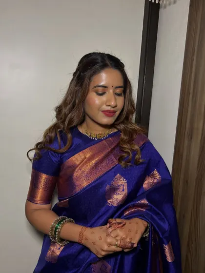A close-up of the bridesmaid's makeup. A soft glam look with a beautiful red lip that complements her blue saree.