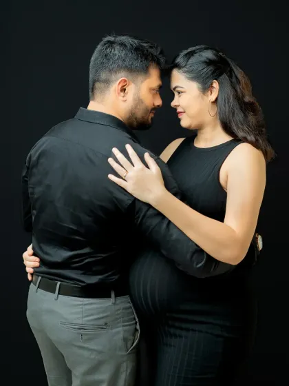 A classic dance-like pose that feels both romantic and elegant. The simple black outfits and background ensure that the couple's interaction is the main story.