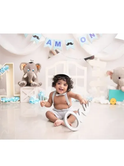 A happy birthday boy in a studio setup decorated with elephants and the name 'Amon'.