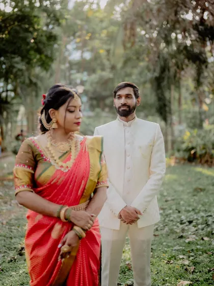 A creative composition using a wider angle. The bride is in the foreground while the groom stands slightly behind, creating a sense of depth and story within the frame.