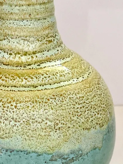 A close-up of the "Coral Coast" glaze on a wheel-thrown vase. The texture is created by the glaze crawling and breaking over the throwing rings.