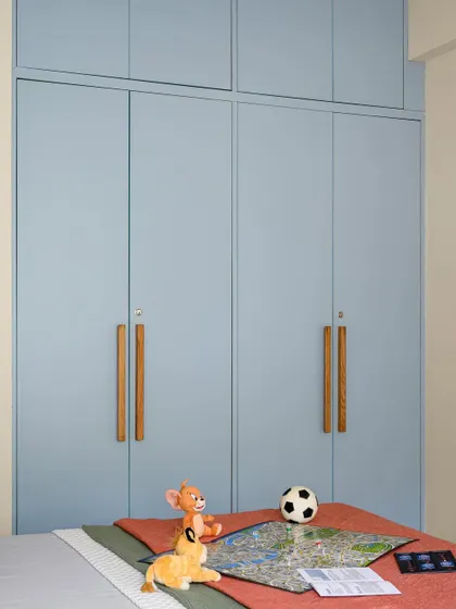 A close-up of the wardrobe in the 'Amy and Joel's room', finished in a calming powder blue with custom wooden handles. The design is simple, clean, and timeless.