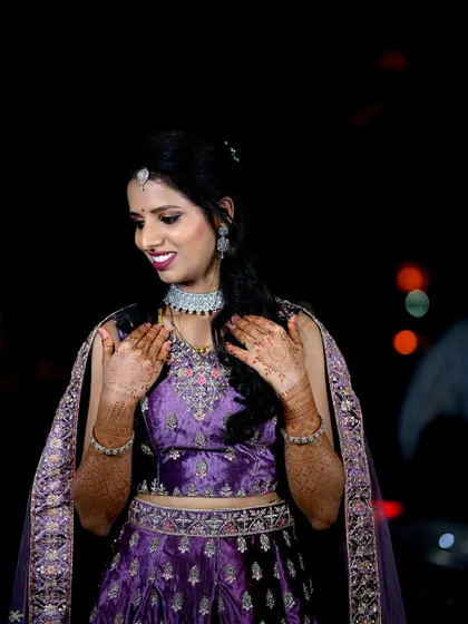 A beautiful portrait of the bride at her evening reception. The dark background makes her purple lehenga and joyful expression stand out.