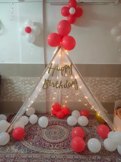 A close-up of our cozy tent decoration, adorned with fairy lights and red and white balloons for a 9th birthday.
