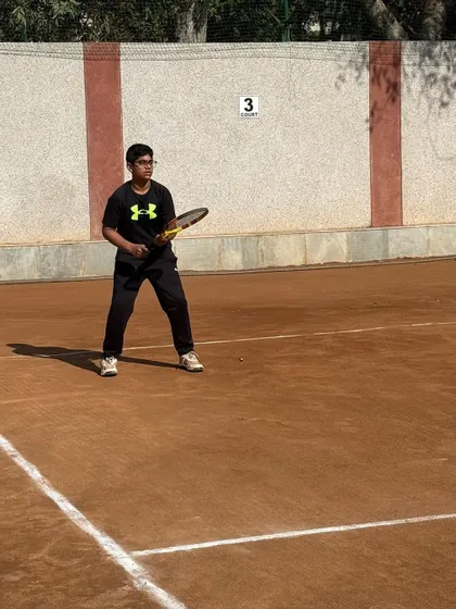 A player preparing for a backhand shot on the clay court. His stance is balanced and ready for a powerful stroke.