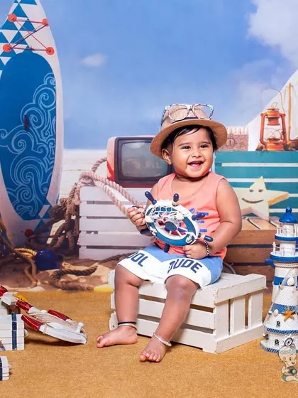 A happy toddler enjoying our beach-themed setup, complete with sand, surfboards, and nautical props. His infectious laugh makes this a perfect summer-themed photograph.