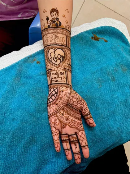 Side view of a detailed baby shower mehendi, showing the flow of the design from the palm up the arm, including a "Baby SV Loading" element.