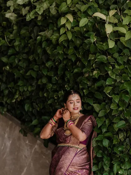 We focus on capturing candid, in-between moments. Here, the mother-to-be adjusts her earring against a lush wall of green leaves, creating a natural and graceful portrait that feels authentic and unposed.