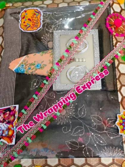 A Holi-themed trousseau packing for a saree, decorated with colorful pom-pom lace and 'Happy Holi' stickers.