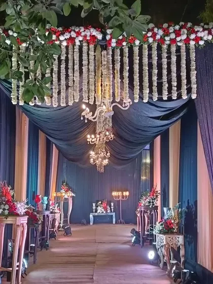I create grand entrance passages that make guests feel special. This walkway uses dark drapes, elegant chandeliers, and fresh red and white flower arrangements to build excitement for the main event area.